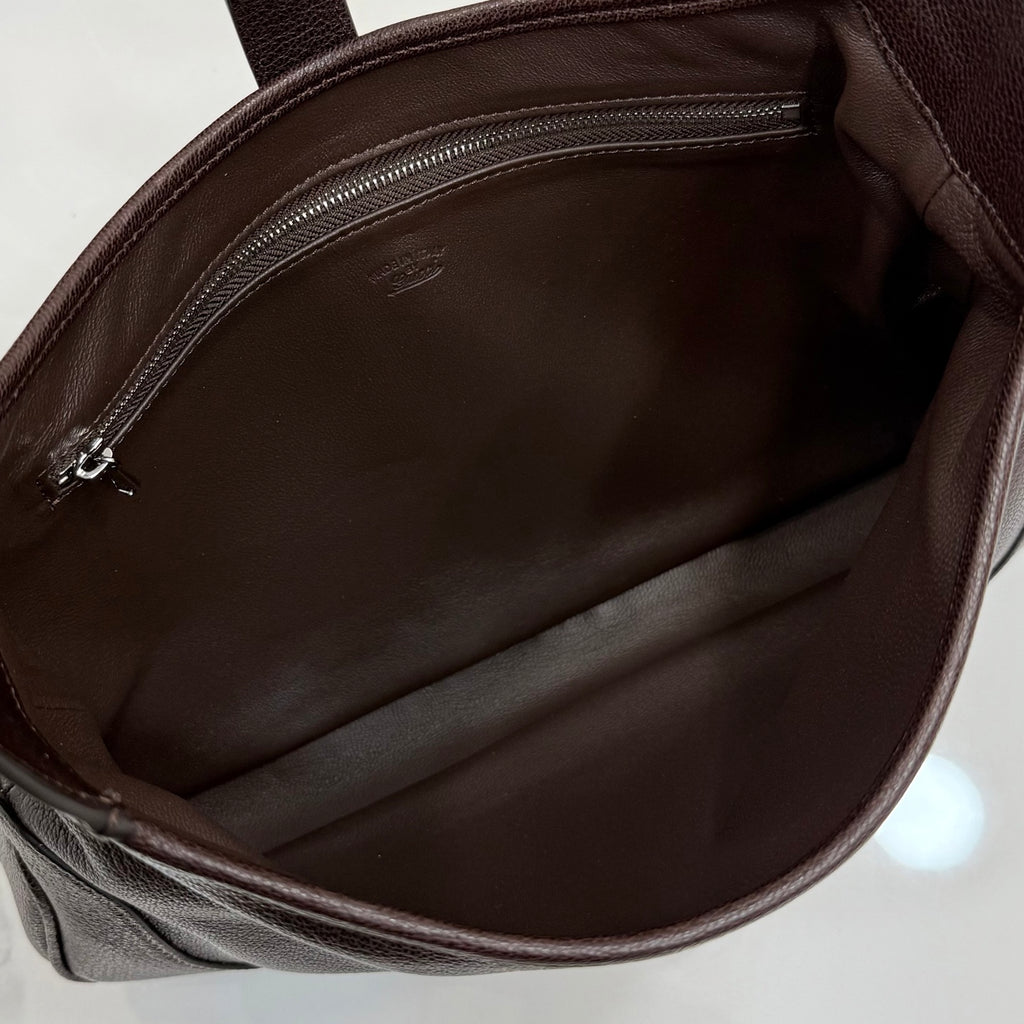 Brown fabric-lined interior of a dark brown leather bag with zipper opening