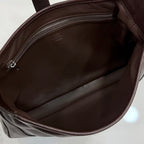 Brown fabric-lined interior of a dark brown leather bag with zipper opening