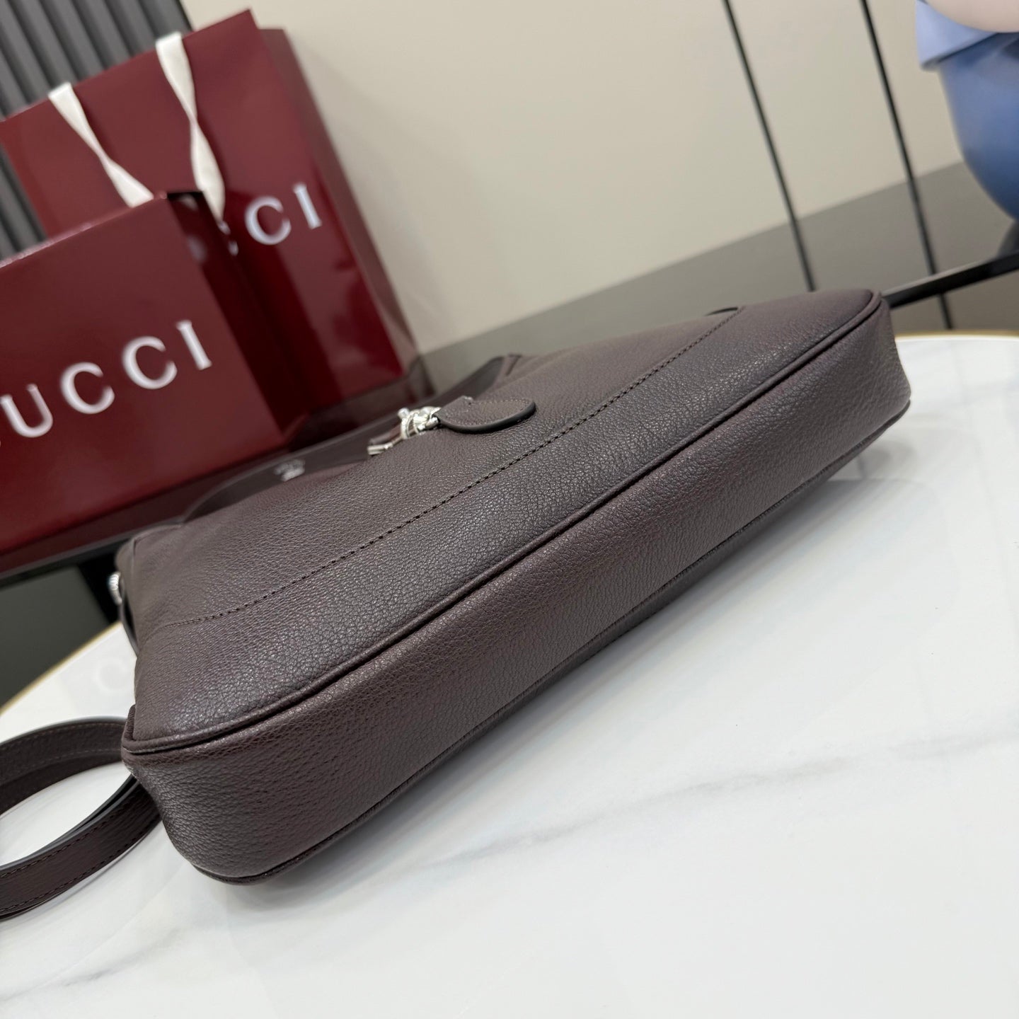 Dark brown leather shoulder bag with top zipper and slim front panel