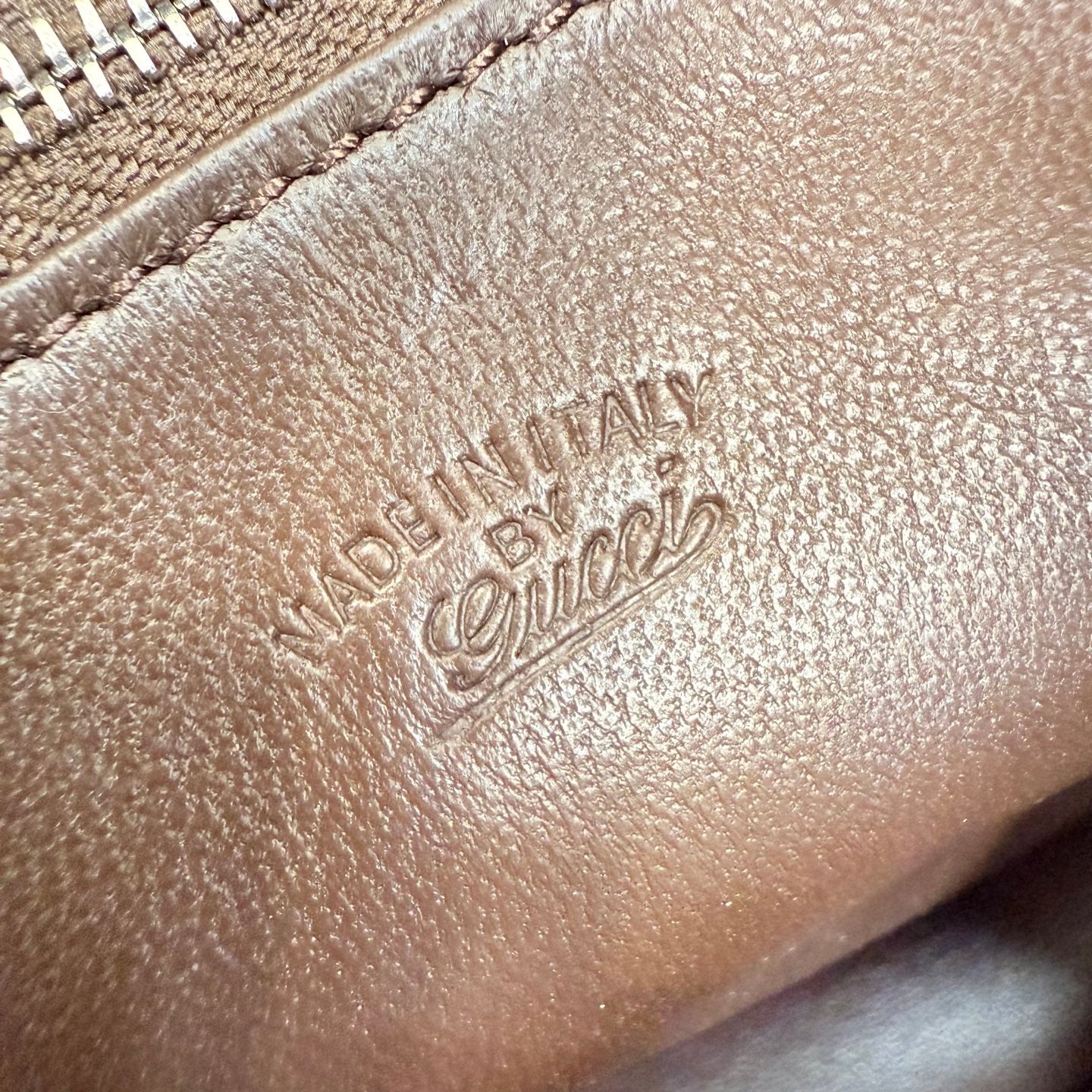 Embossed Made in Italy logo on brown leather bag exterior