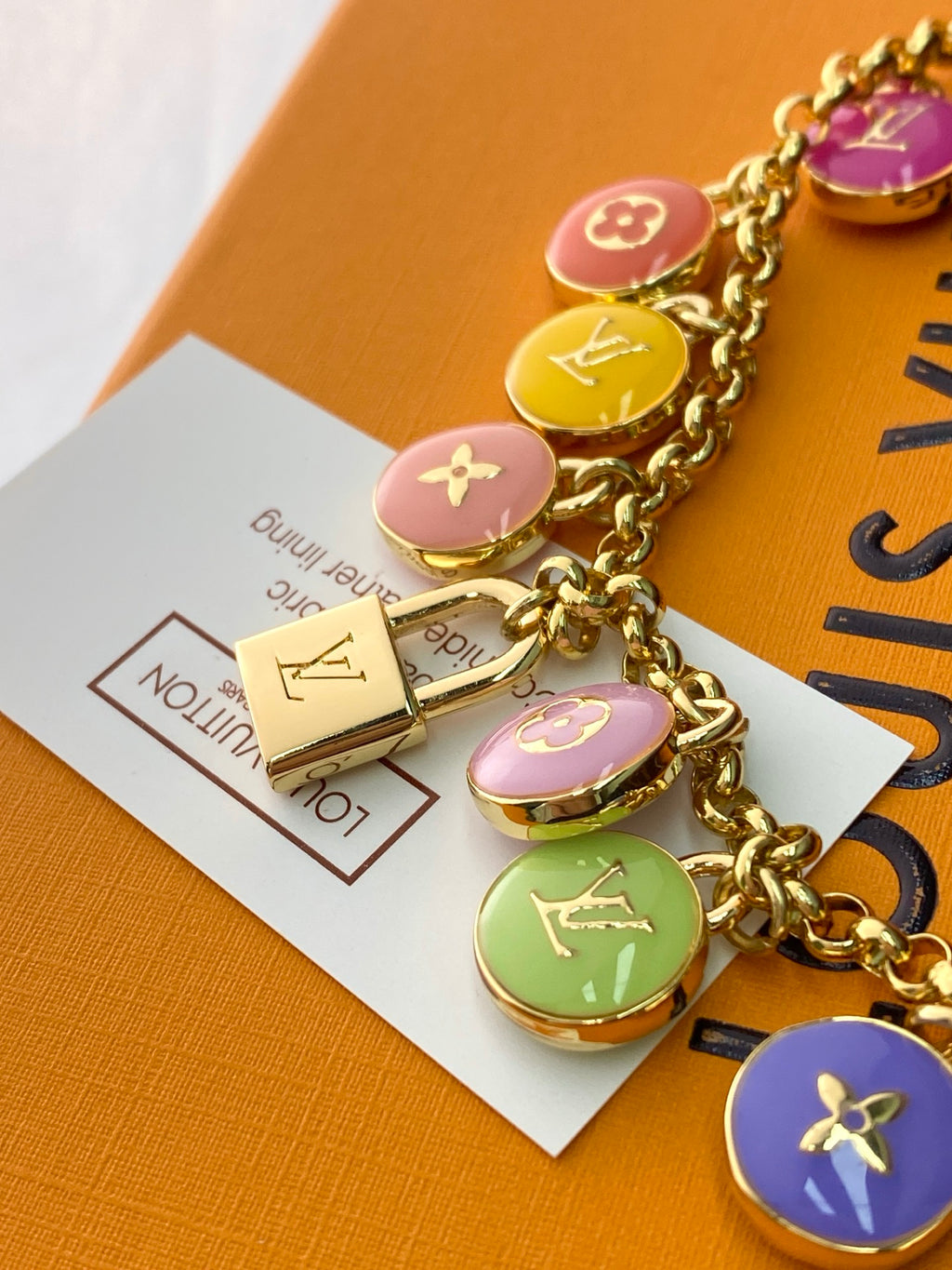Louis Vuitton bag charm set with gold chain and purple, pink, and green round charms