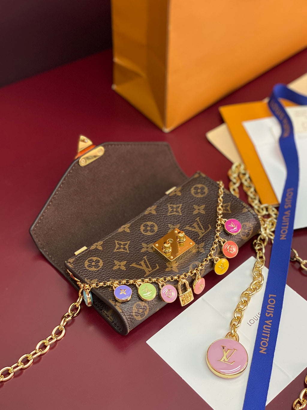 Louis Vuitton small bag with monogram canvas, gold chain strap, colorful charm details