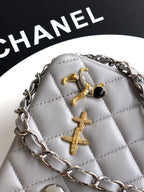 Close-up of quilted leather mini bag with gold-tone cross charms, gray