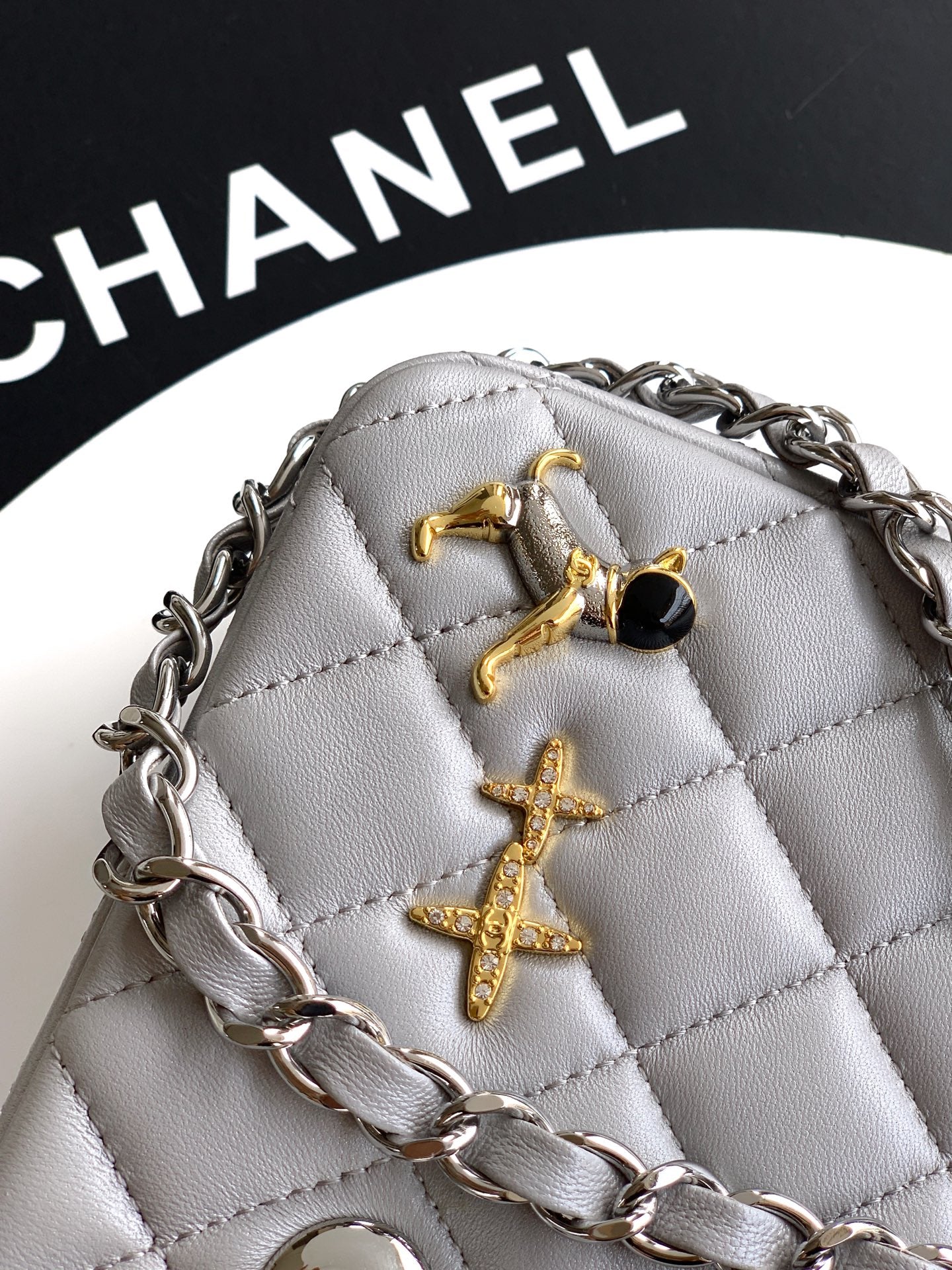Close-up of quilted leather mini bag with gold-tone cross charms, gray