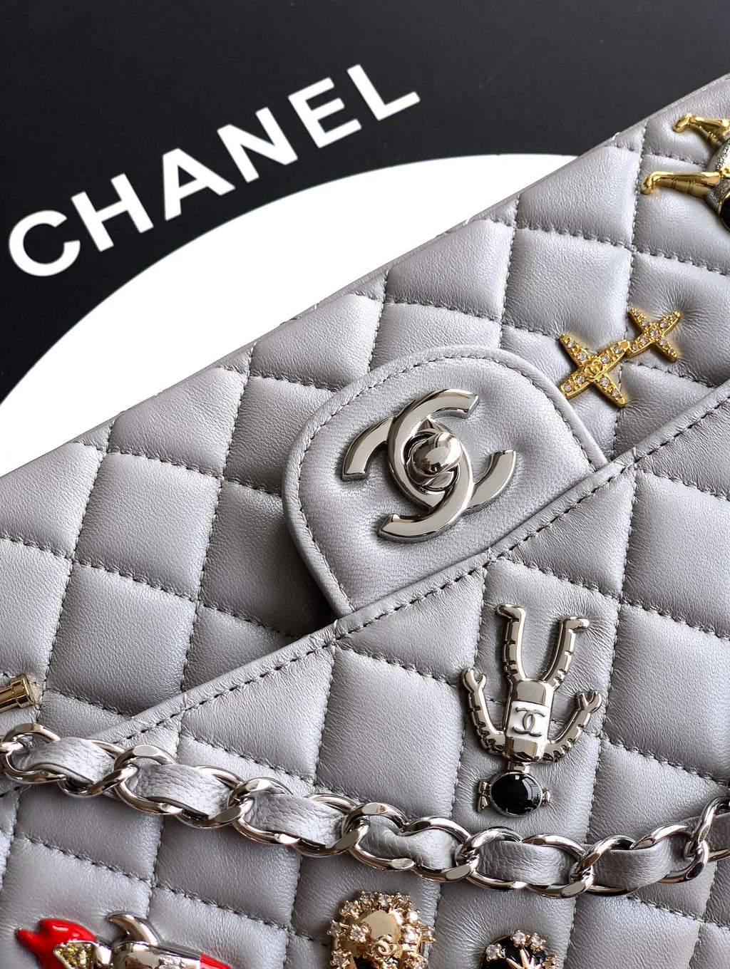 Chanel quilted light gray bag close-up with CC medallion, stud charms, and chain