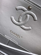 Chanel light gray leather bag close-up with embossed CC logo and stitched details