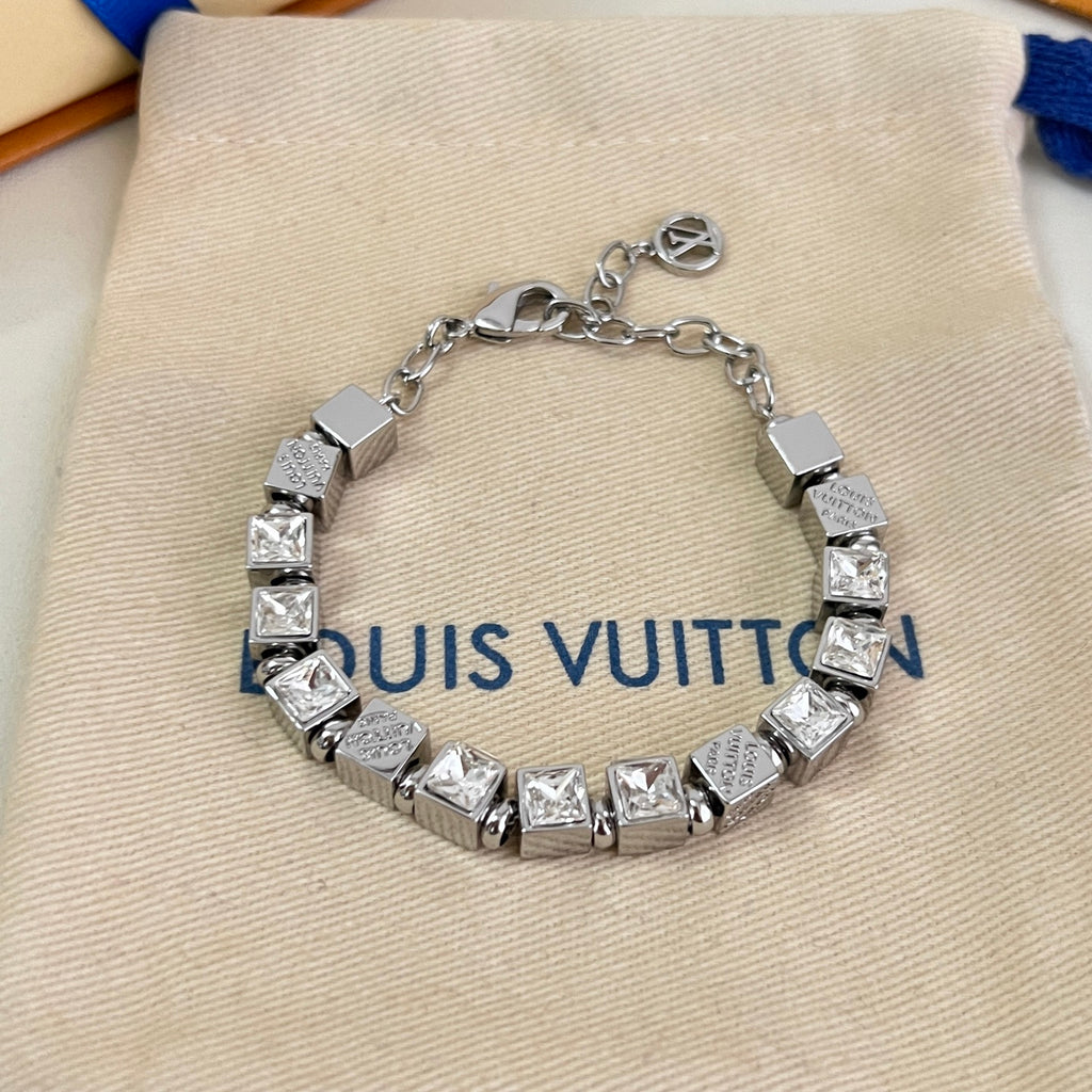 Close-up: silver rhinestone charm bracelet with square links and logo detail
