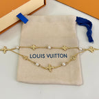Gold-tone charm necklace with pearl beads and star pendants on beige pouch