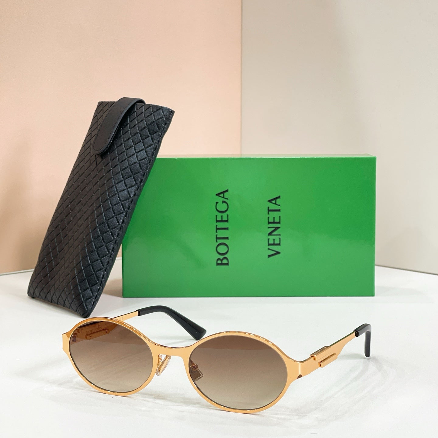 Gold-tone round sunglasses with light brown-tinted lenses and black quilted case