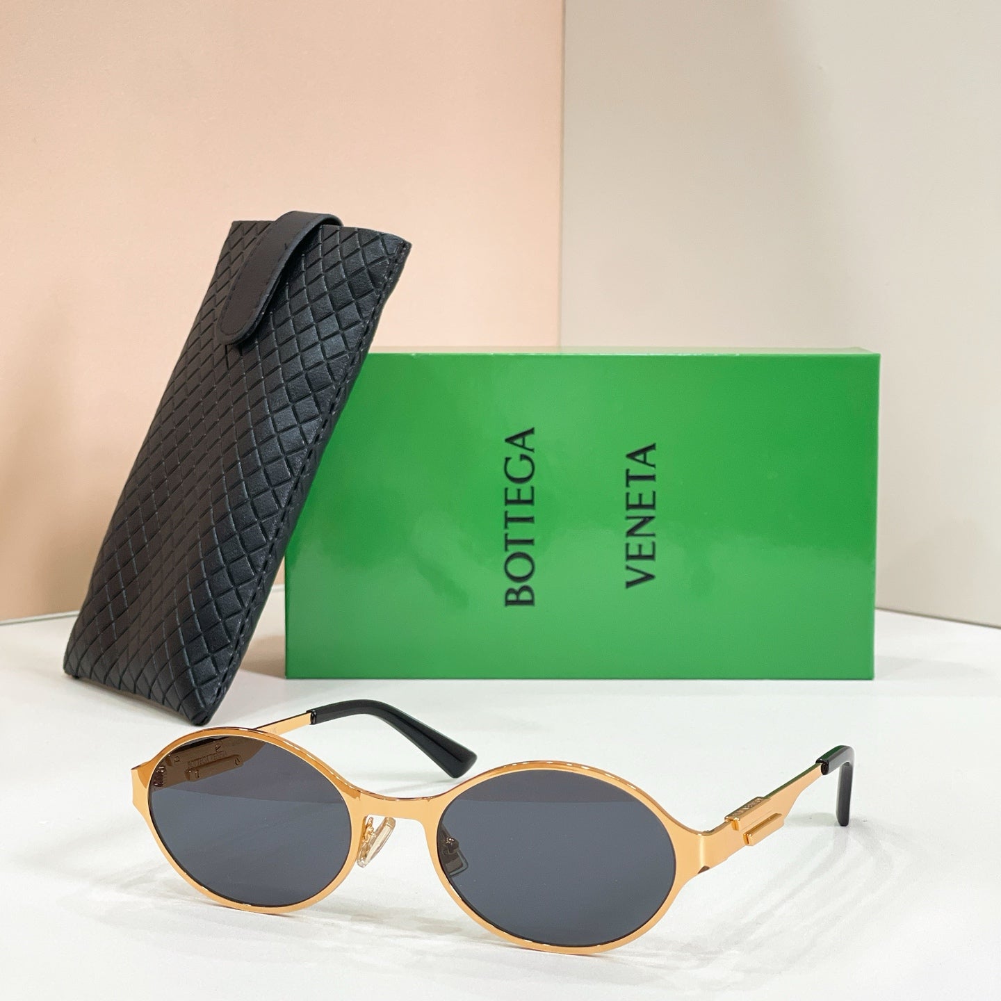 Gold-tone round sunglasses with dark lenses and black quilted case