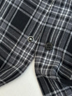 Close-up of plaid long-sleeve shirt with dark buttons and metal snap near hem