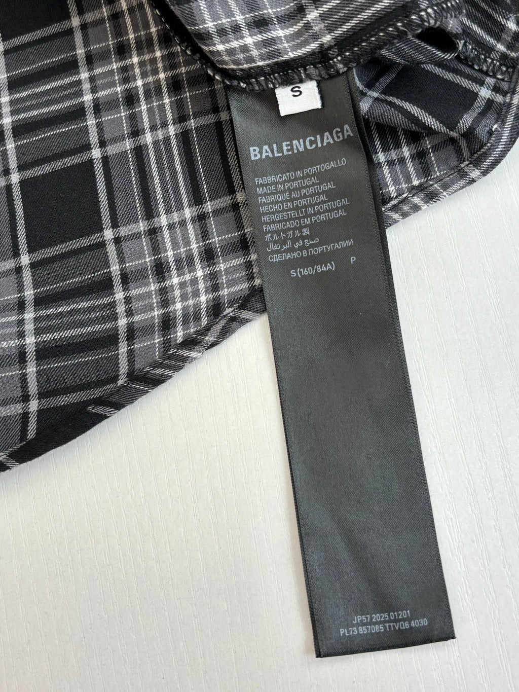 Inside label on black-and-white plaid hooded shirt showing BALENCIAGA product details