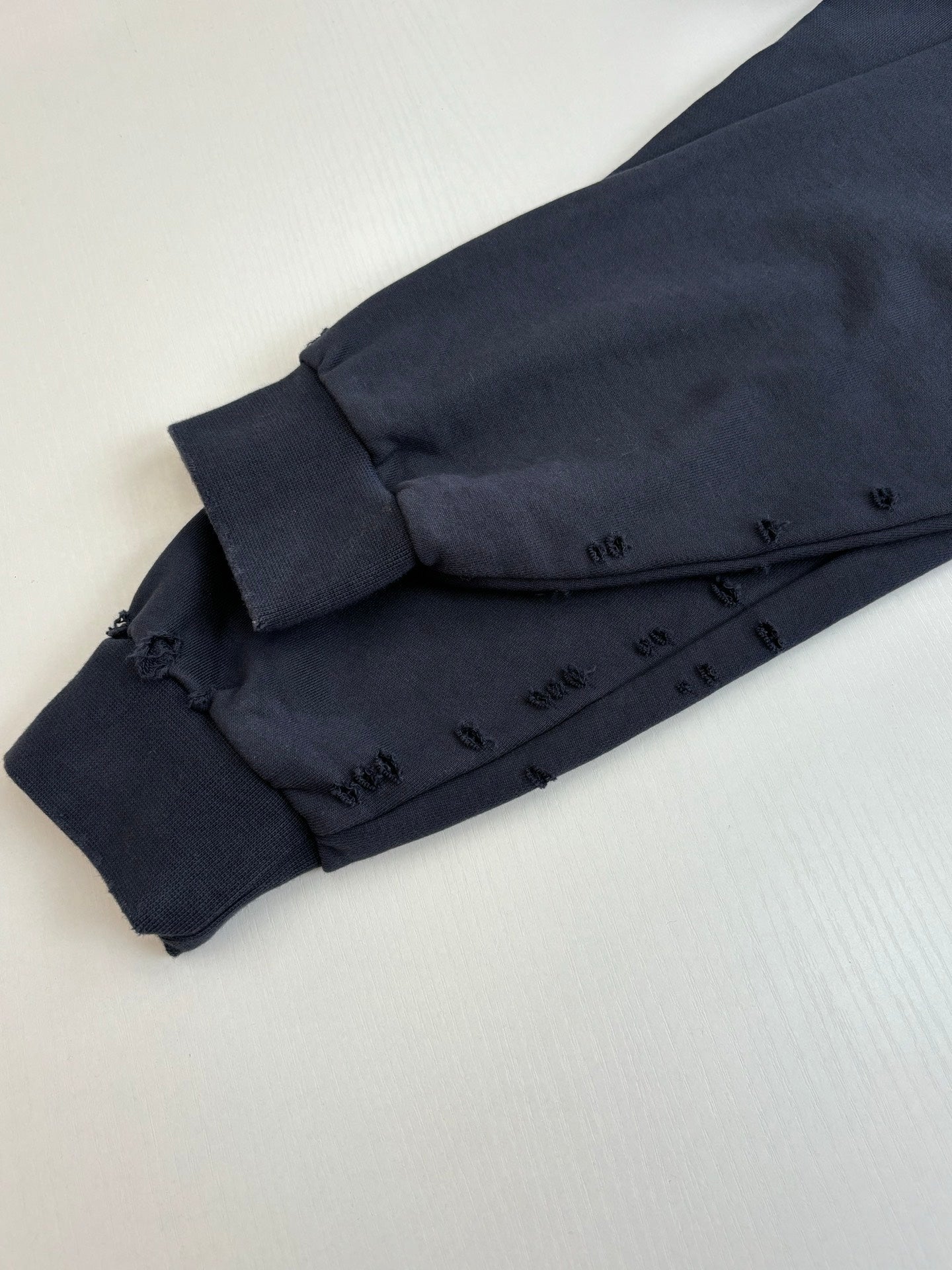 Bottom hem detail of dark navy long-sleeve hooded shirt with stitched facing