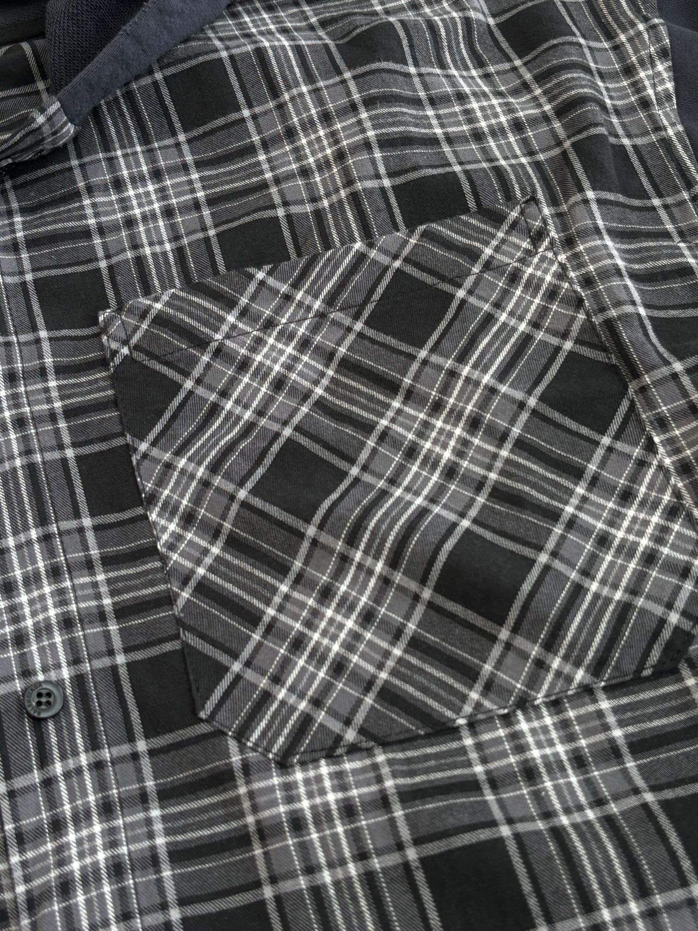Detail view of black-and-white plaid long-sleeve hooded shirt fabric and buttons