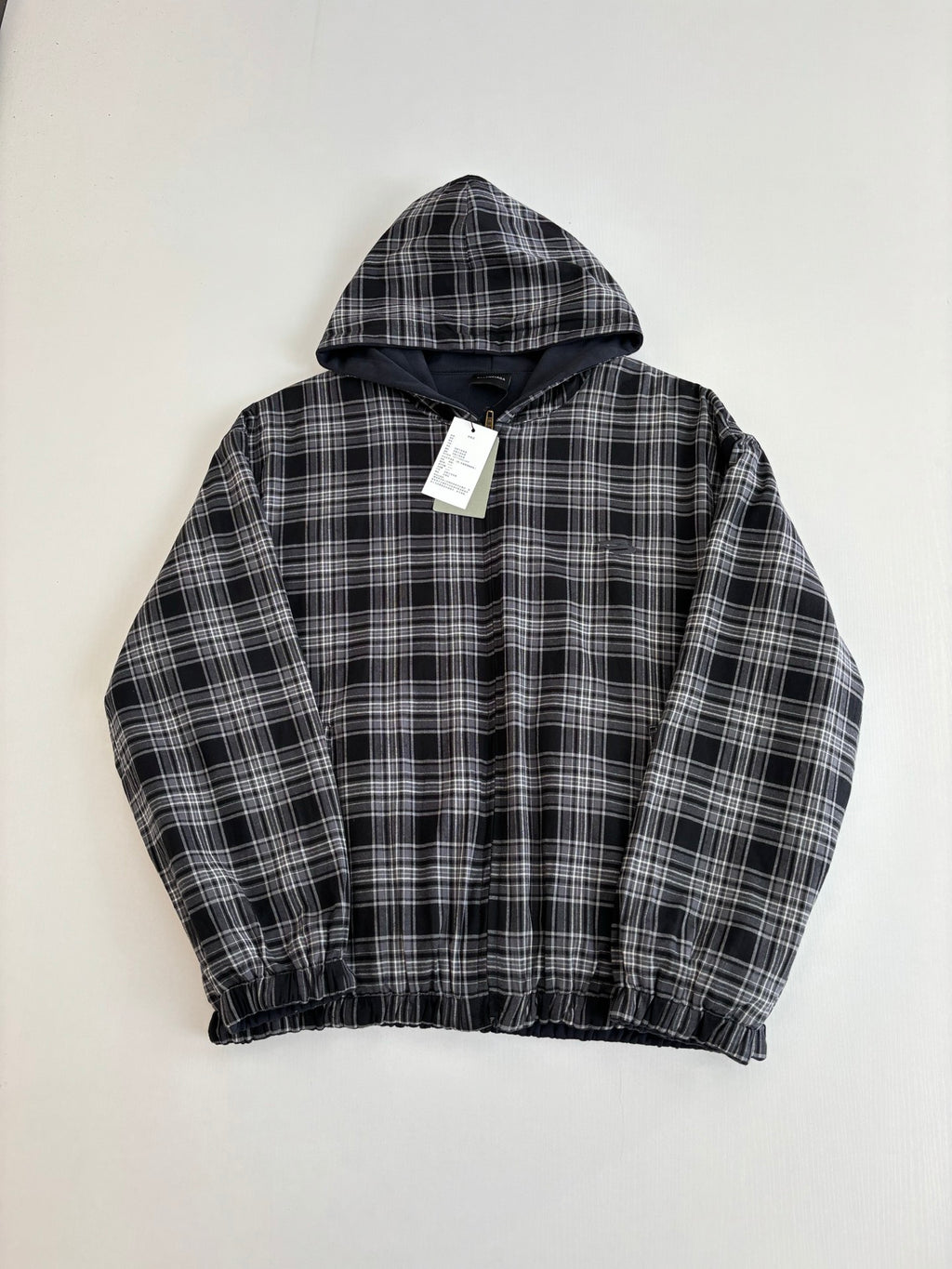 Black and white plaid zip-up hooded jacket with hood, elastic hem, and hang tag