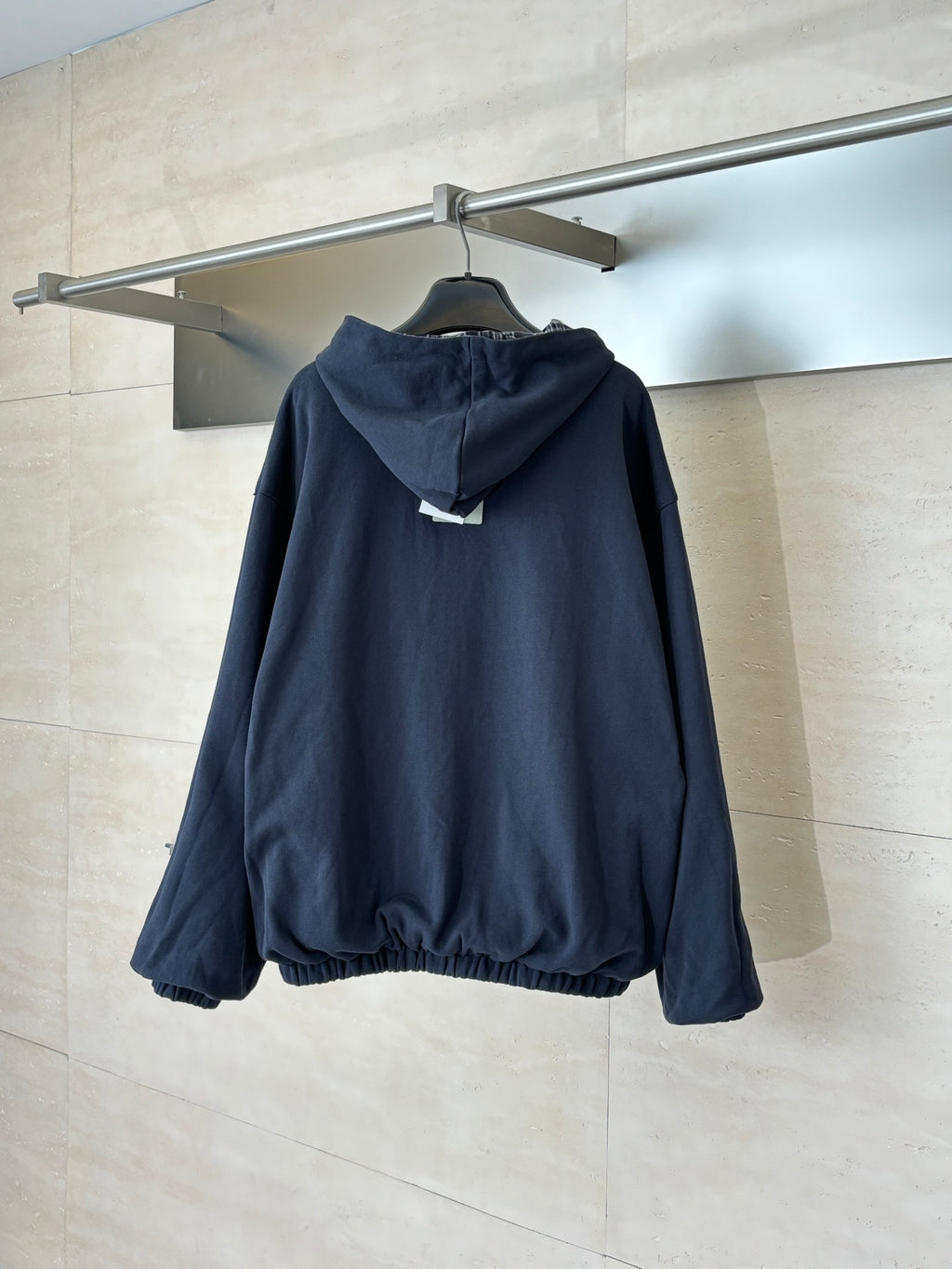 Zip-up hooded jacket in dark navy, shown from back with hood and elastic hem