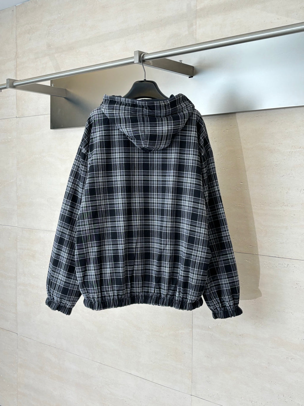 Zip-up hooded jacket in black and white plaid, shown from back with hood and zipper