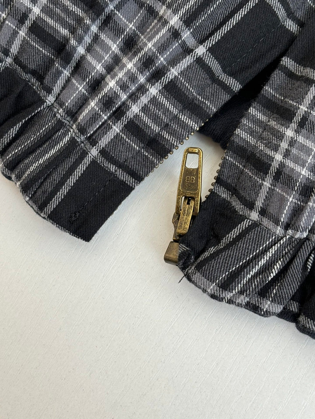 Black and white plaid jacket zipper with metal pull tab close-up