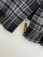 Black and white plaid jacket zipper with metal pull tab close-up