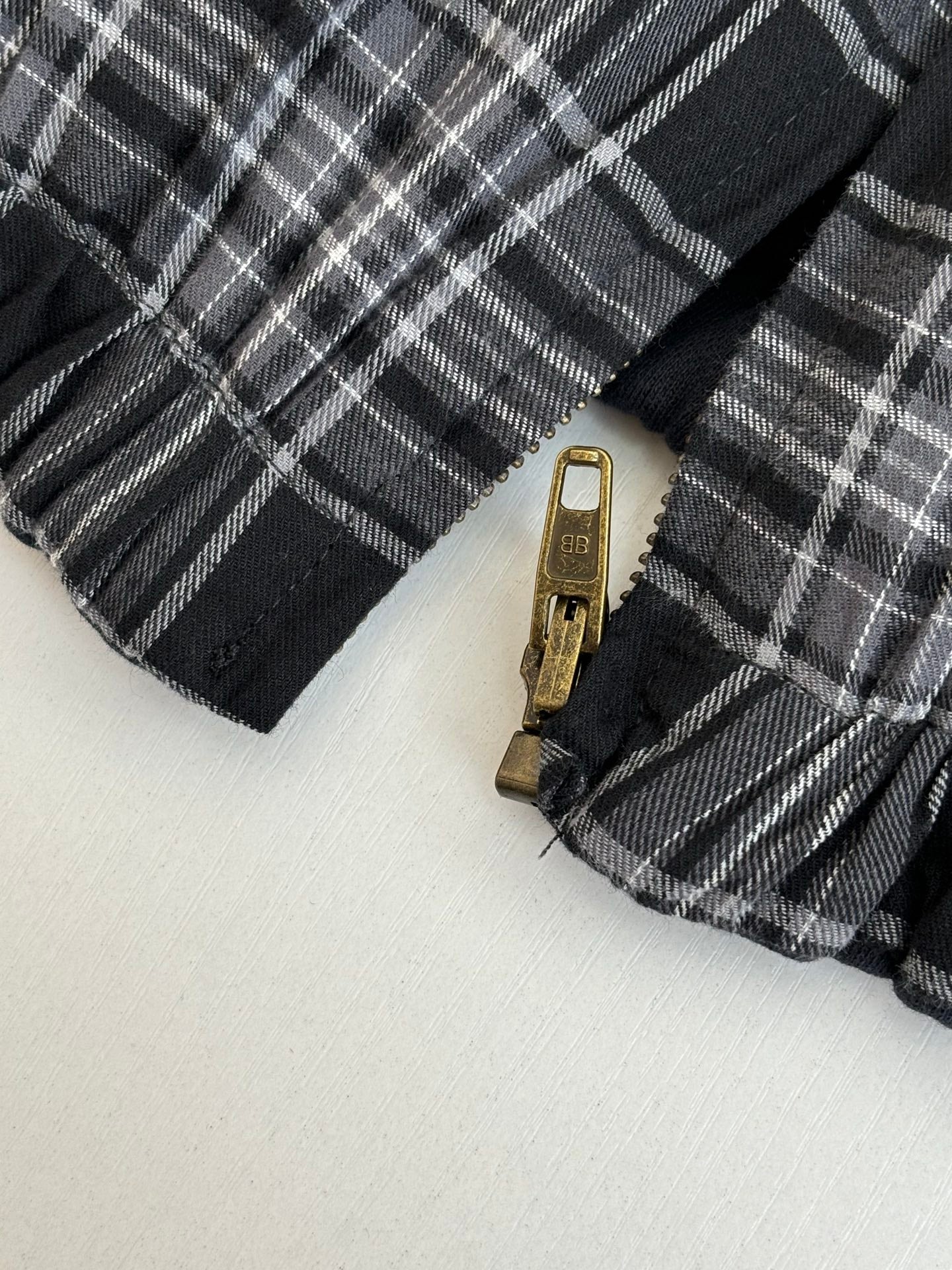 Black and white plaid jacket zipper with metal pull tab close-up
