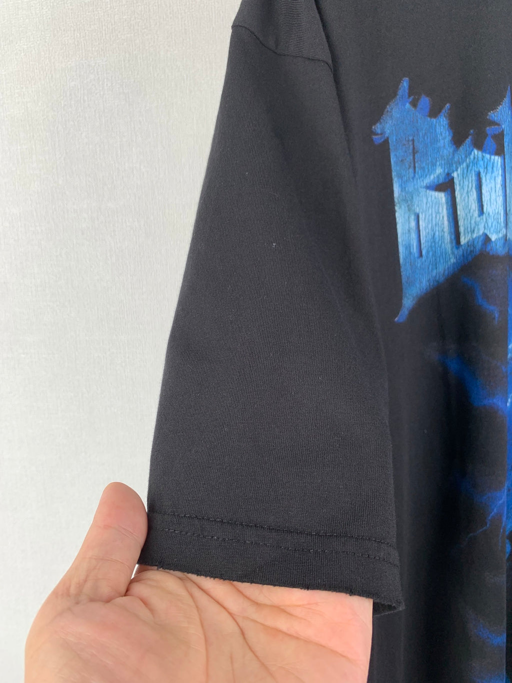 Black T-shirt hem and side seam detail with partial blue graphic