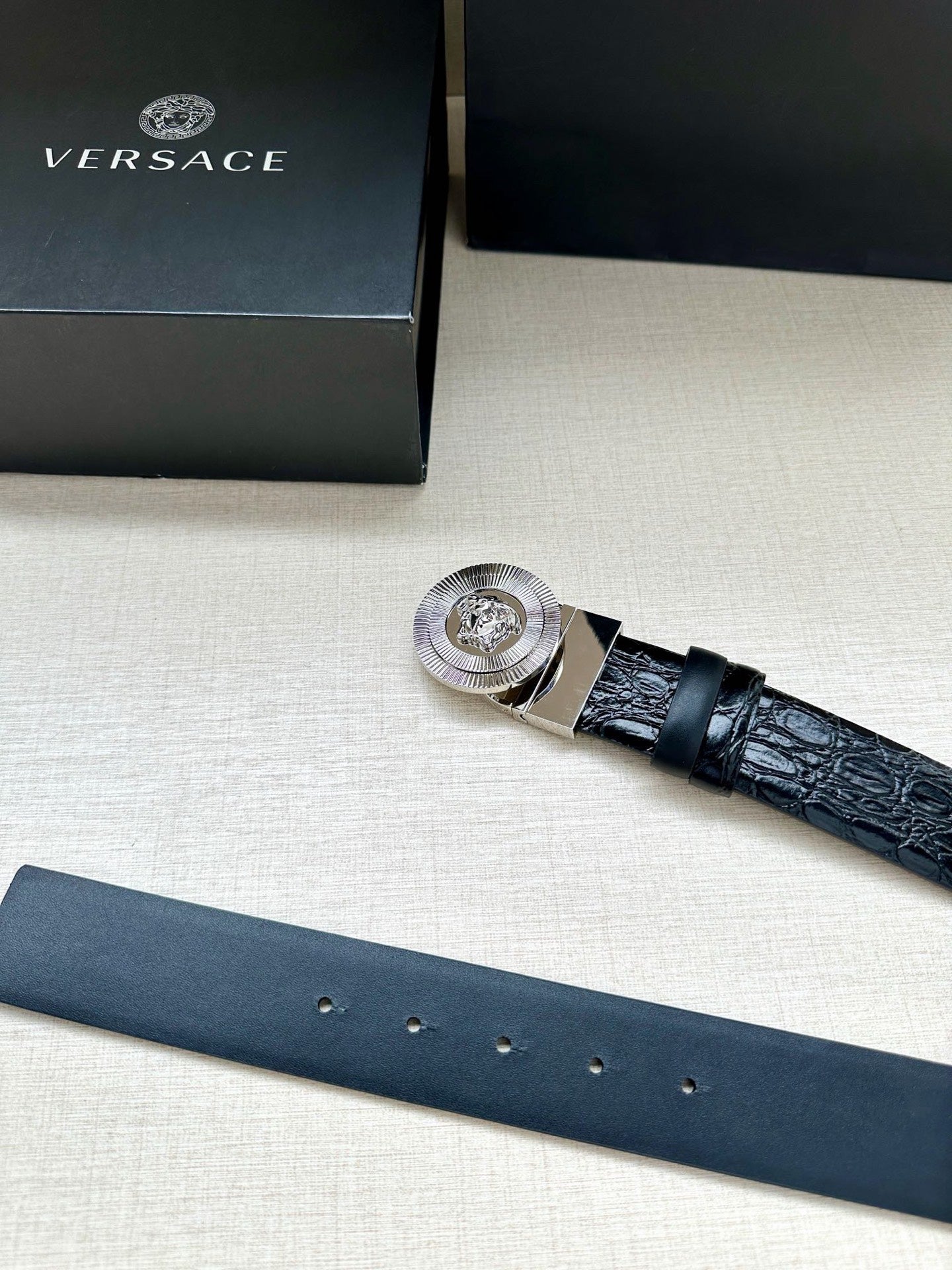 Dark blue leather belt with silver buckle and embossed texture, angled view