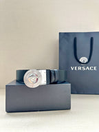 Dark blue leather belt with round silver Medusa buckle, laid on box