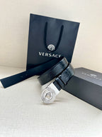 Dark blue leather belt with round silver Medusa buckle, resting on boxes