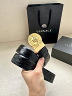 Dark embossed leather belt in hand with gold Medusa round buckle