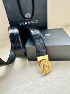 Dark embossed leather belt with gold Medusa round buckle and perforated strap