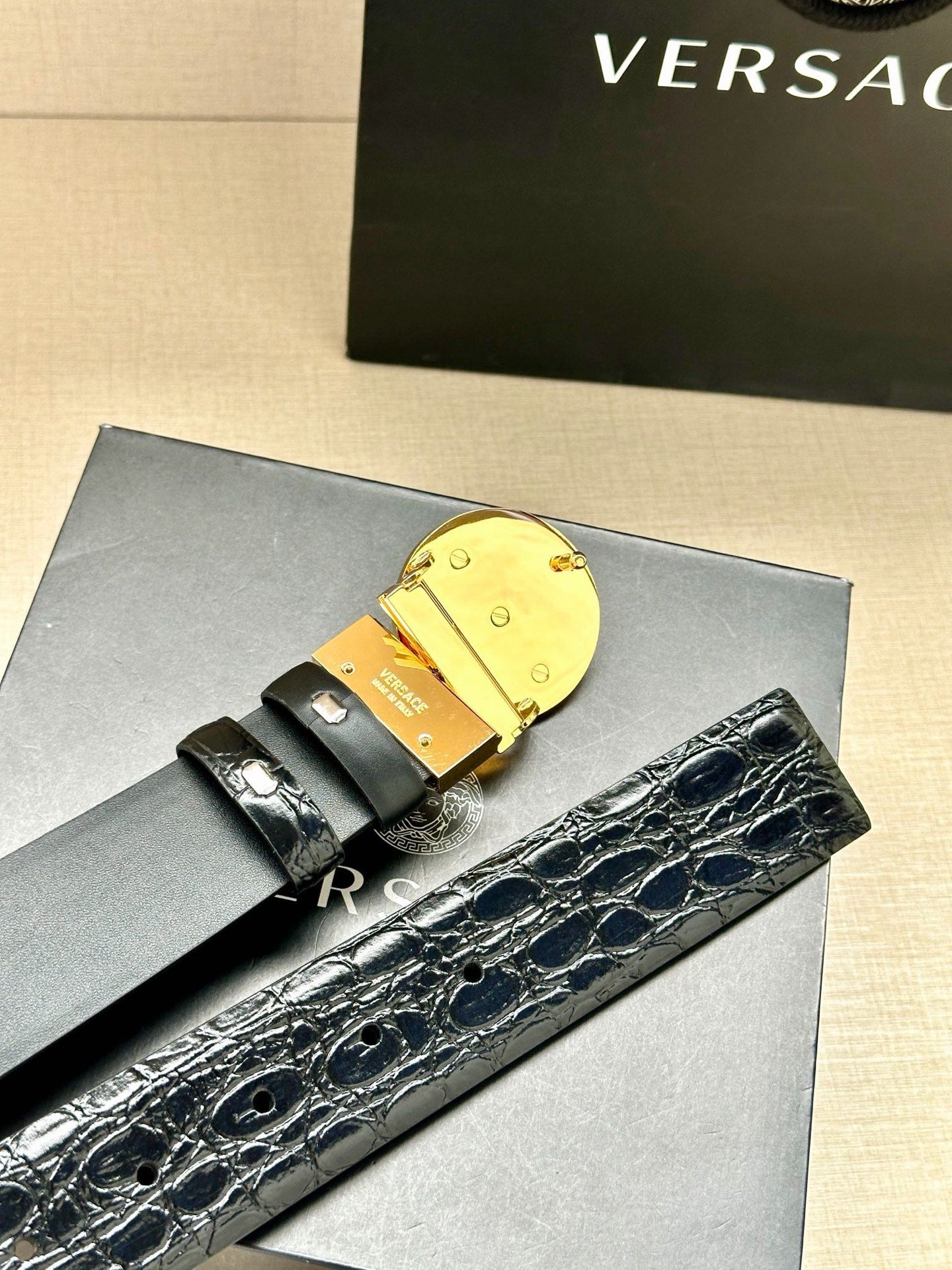Embossed dark leather belt with gold Medusa buckle and gold-toned bar