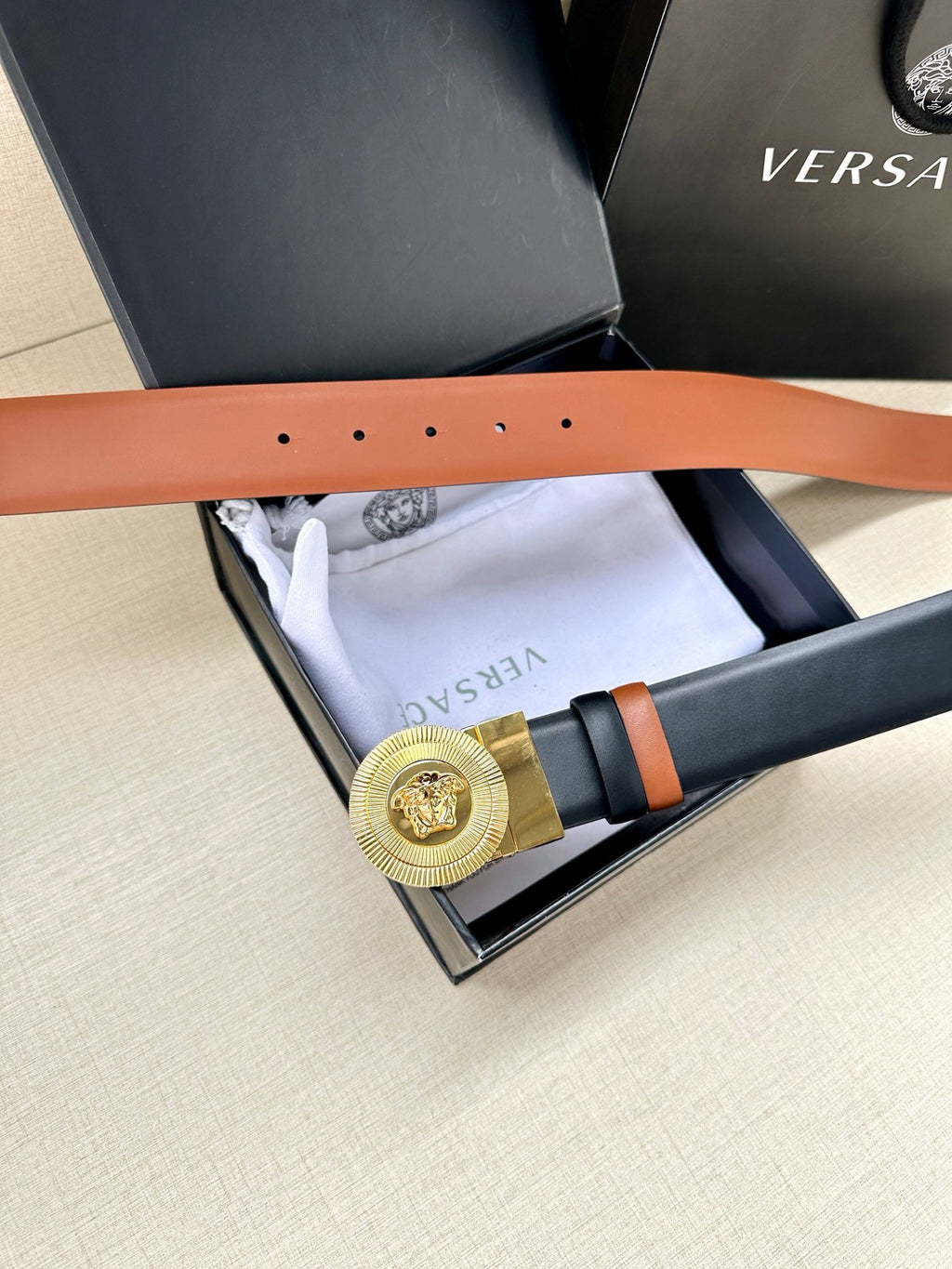 Versace belt laid in box: gold medallion buckle, dark navy leather with orange strap trim