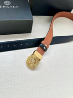 Versace belt detail: gold medallion buckle on dark navy leather, orange edge trim