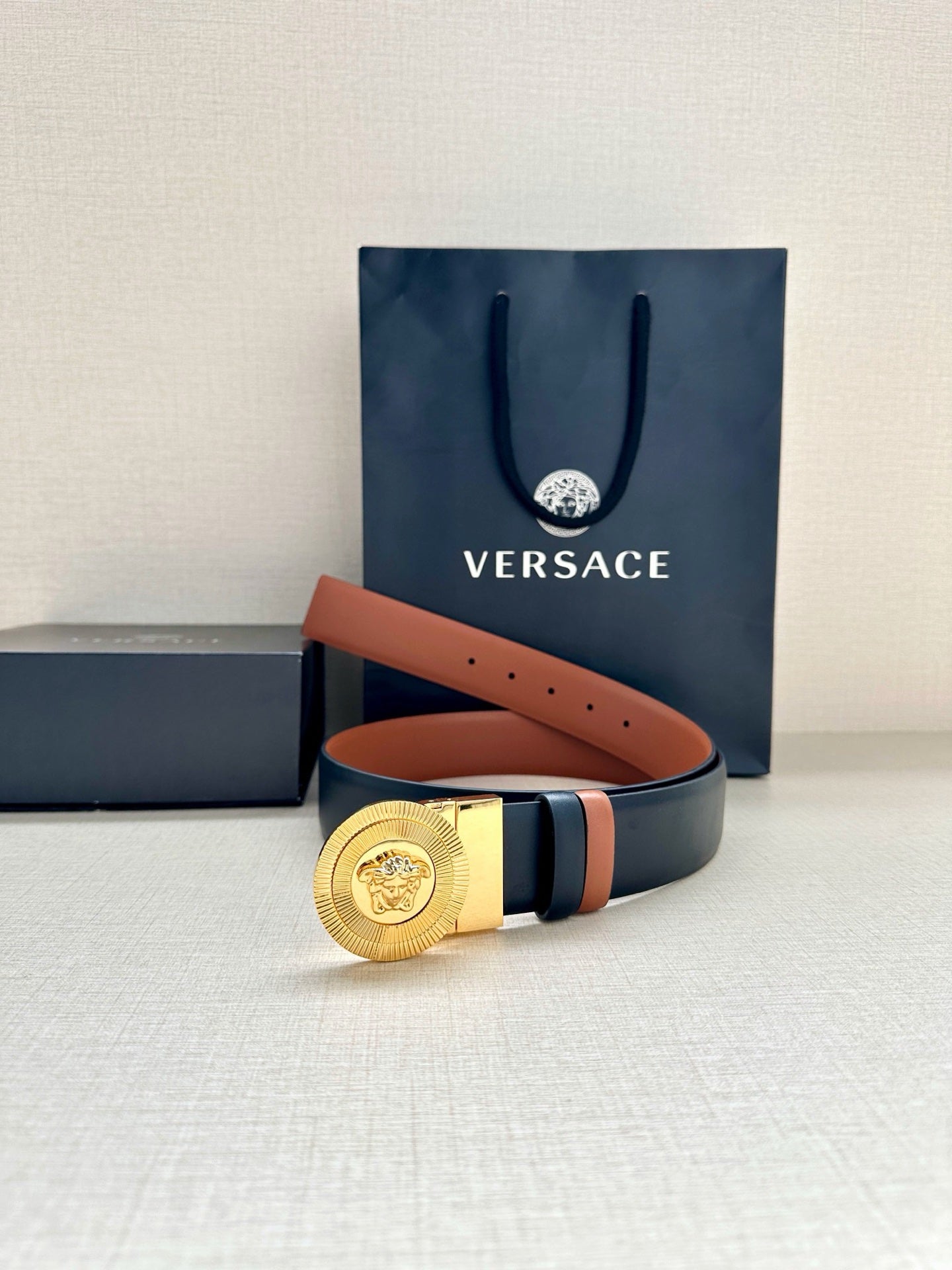 Versace belt with gold medallion buckle, dark navy strap and orange underside accent