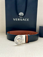 Dark navy leather belt with round silver Medusa buckle and tan interior lining