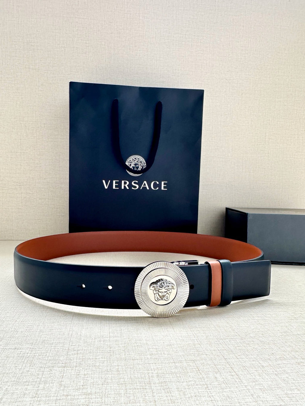 Belt in dark navy leather with round silver Medusa buckle and tan strap lining