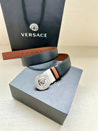 Navy leather belt with round silver Medusa buckle on a tan-lined strap
