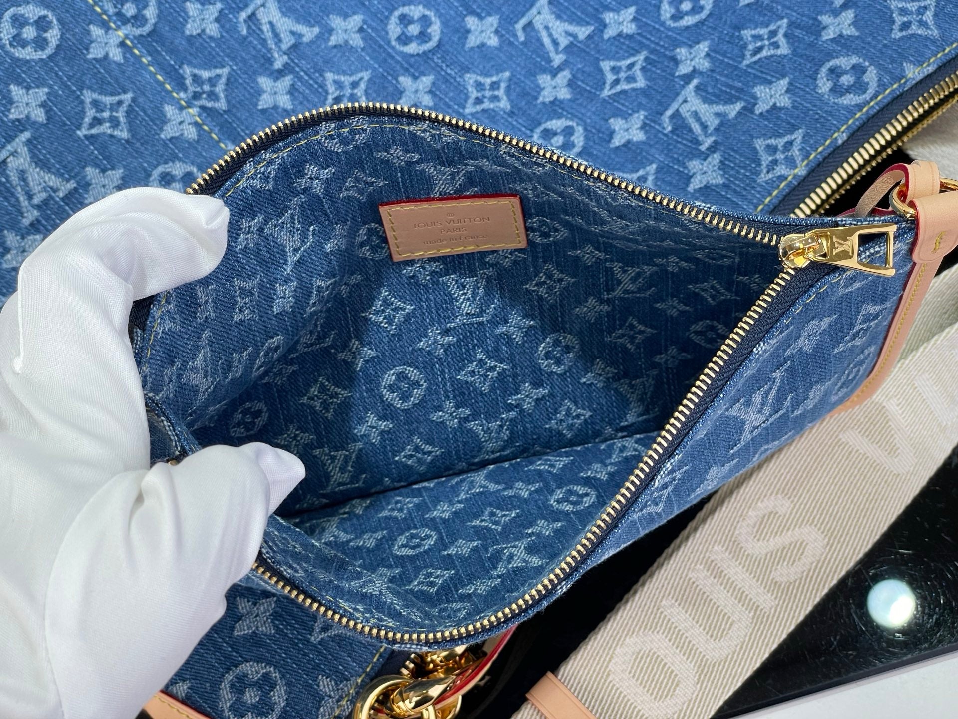 Louis Vuitton bag open view with blue monogram lining, zipper, and tan leather patch
