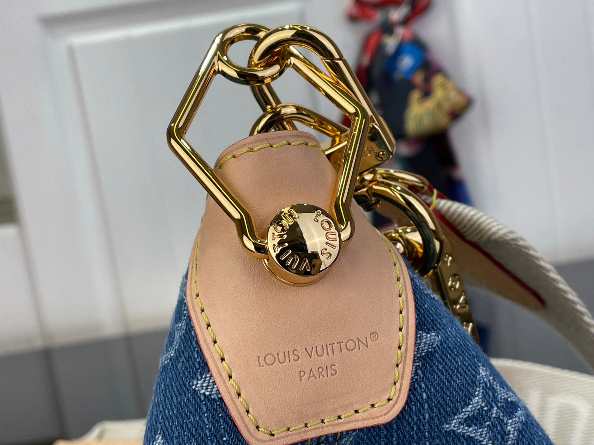 Louis Vuitton hobo bag handle close-up with gold-tone chain and tan leather patch
