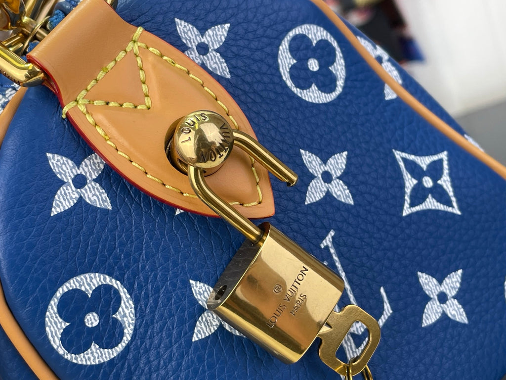 Louis Vuitton blue monogram bag close-up of gold lock on tan leather strap