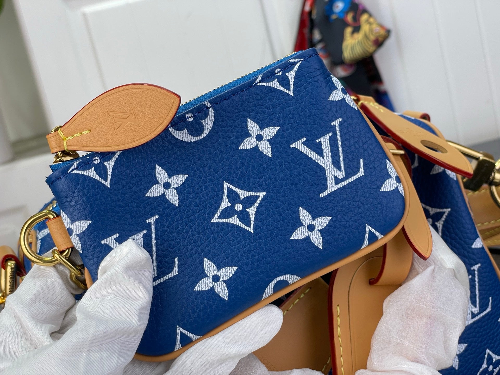 Louis Vuitton bag with blue monogram pattern and tan leather strap, small gold hardware