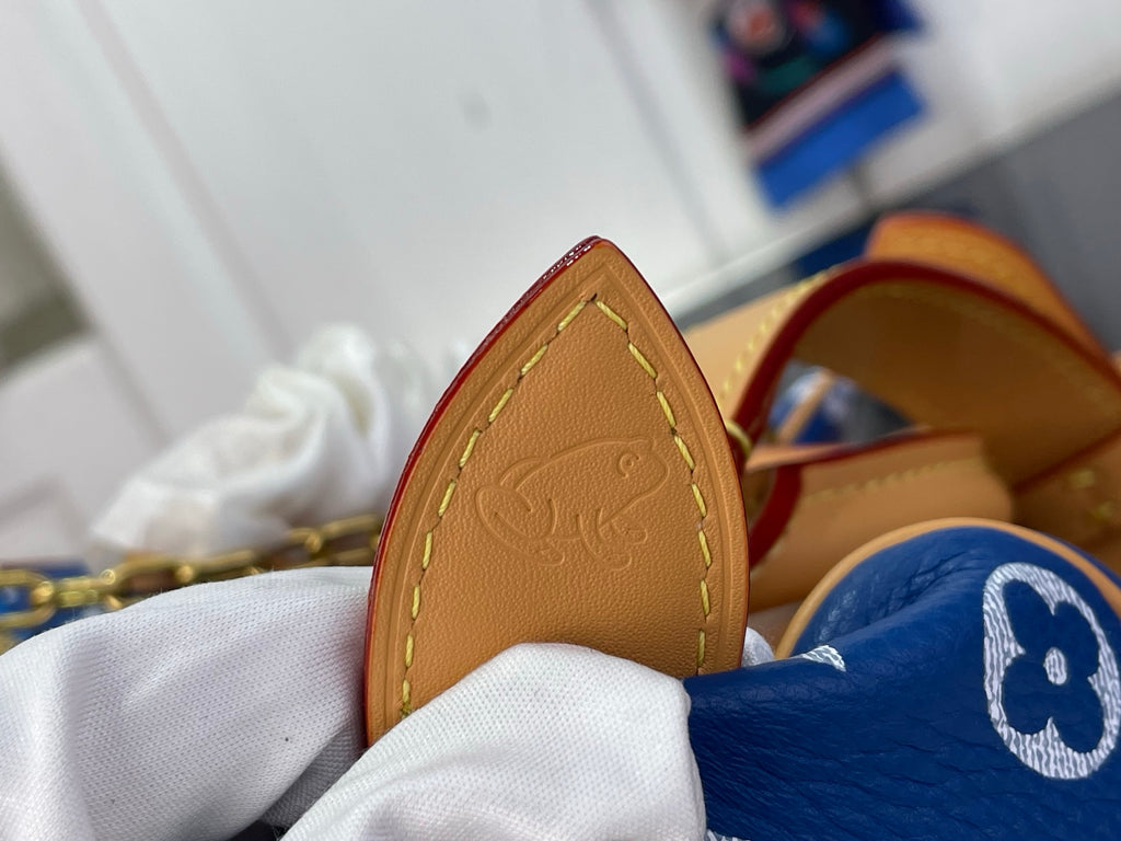Louis Vuitton bag corner with tan leather edge and stitched panel, blue monogram fabric visible