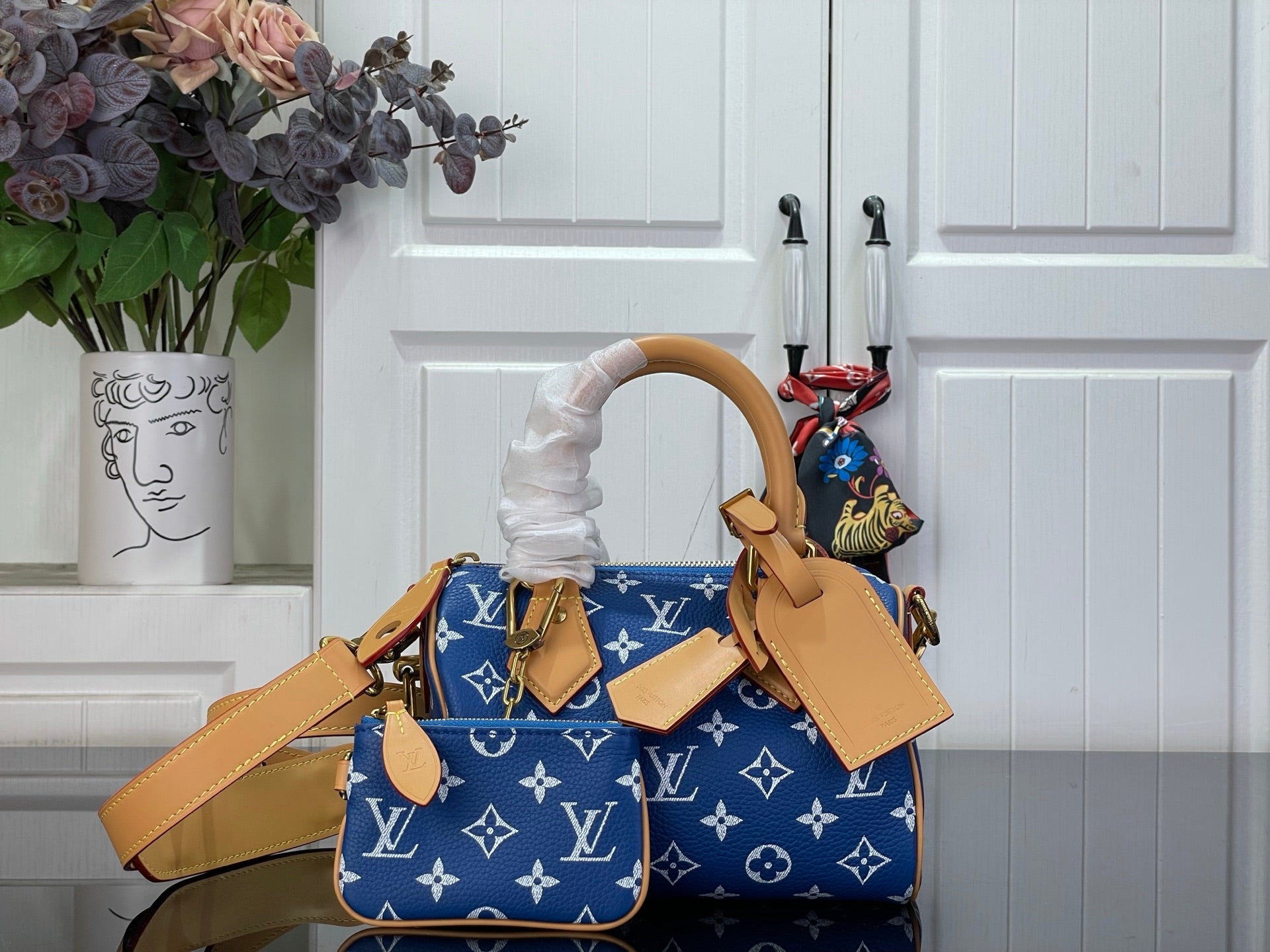 Louis Vuitton blue monogram bag with tan handles and front luggage tags