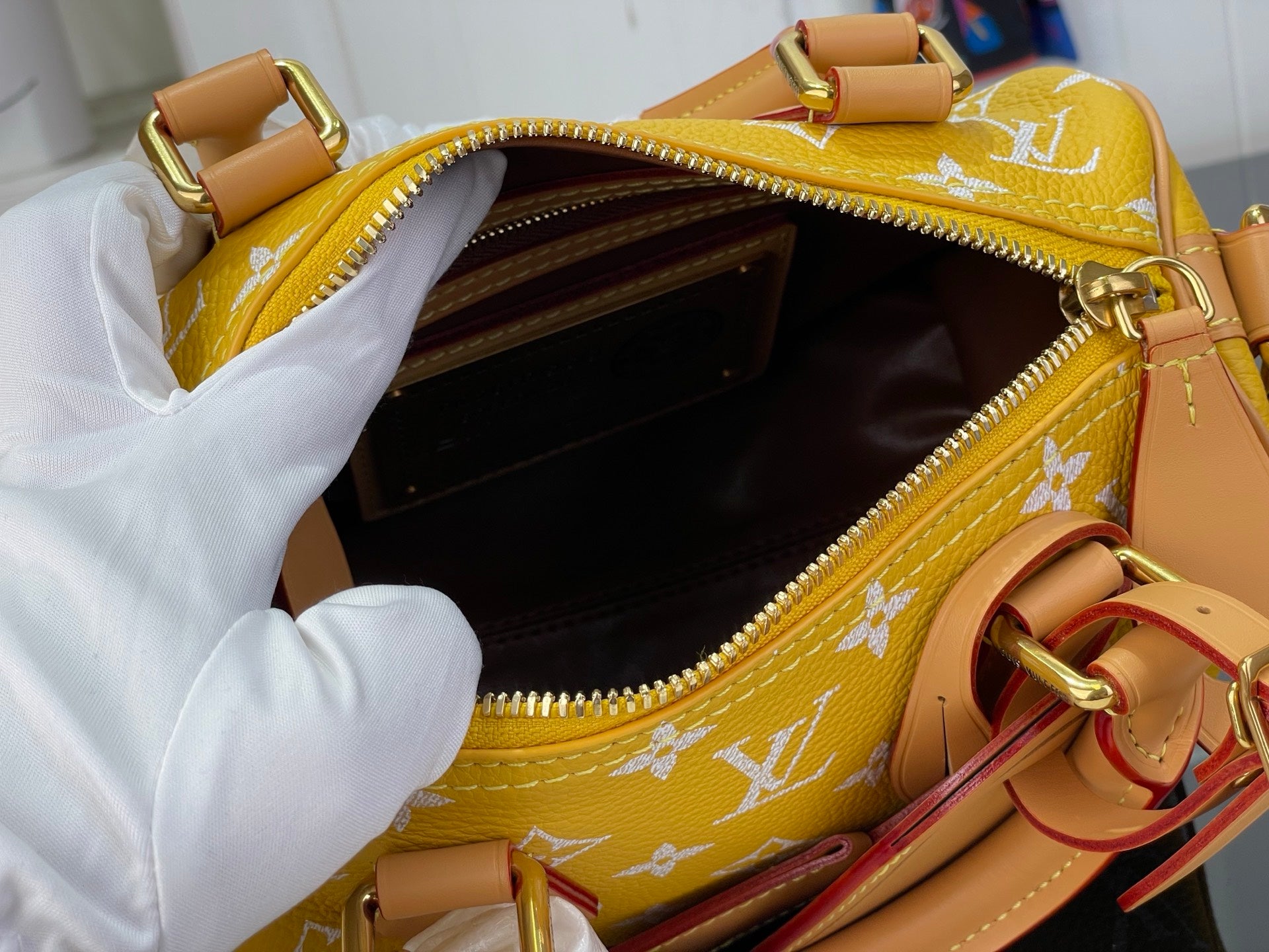 Louis Vuitton bag with open zip showing brown interior and yellow monogram canvas.