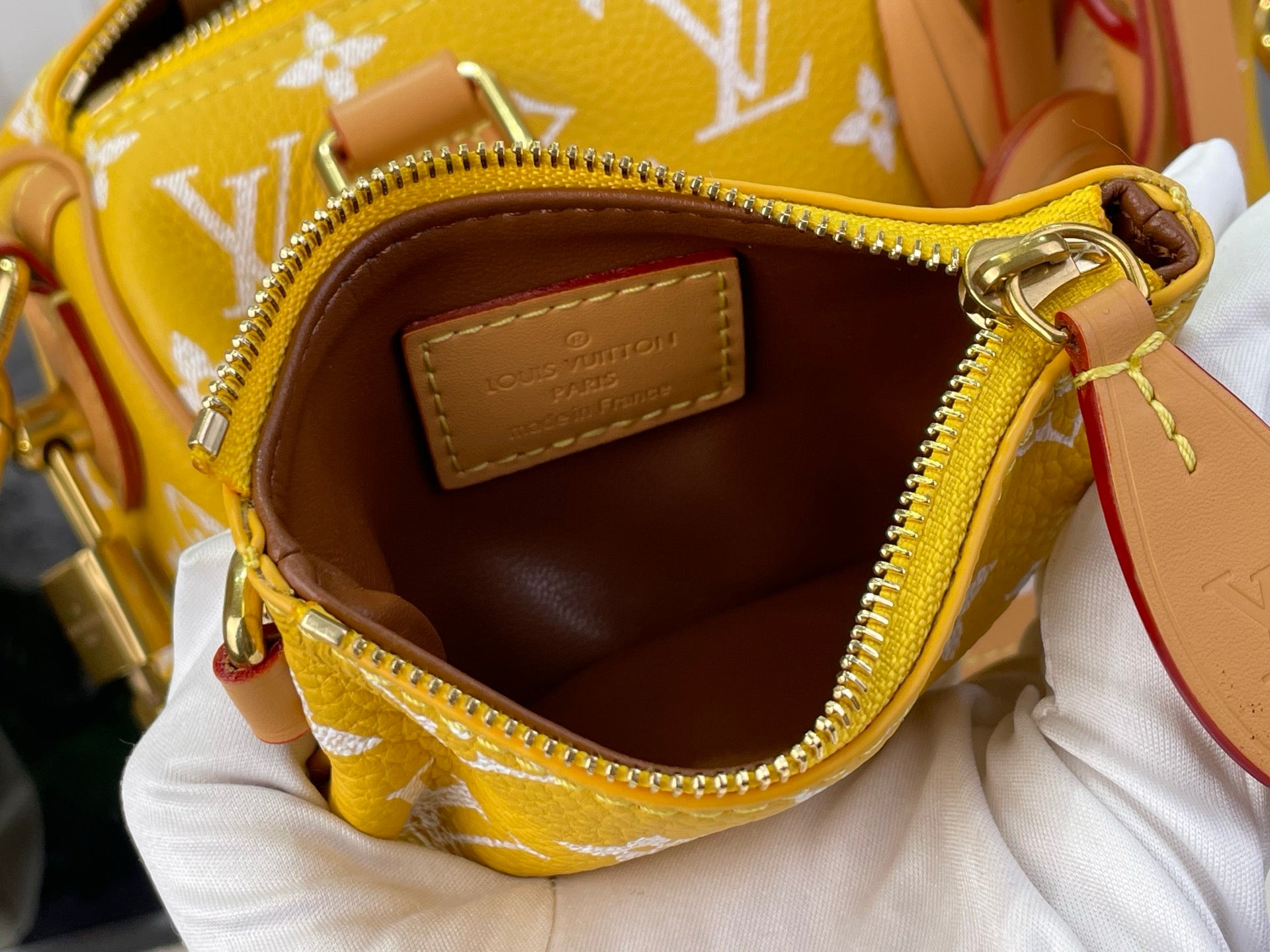 Louis Vuitton bag interior pocket with brown lining and stitched leather label.