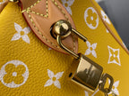 Designer handbag close-up: round snap and gold D-ring on yellow monogram leather