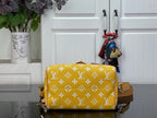 Designer handbag with yellow monogram pattern and tan trim, front flap closed