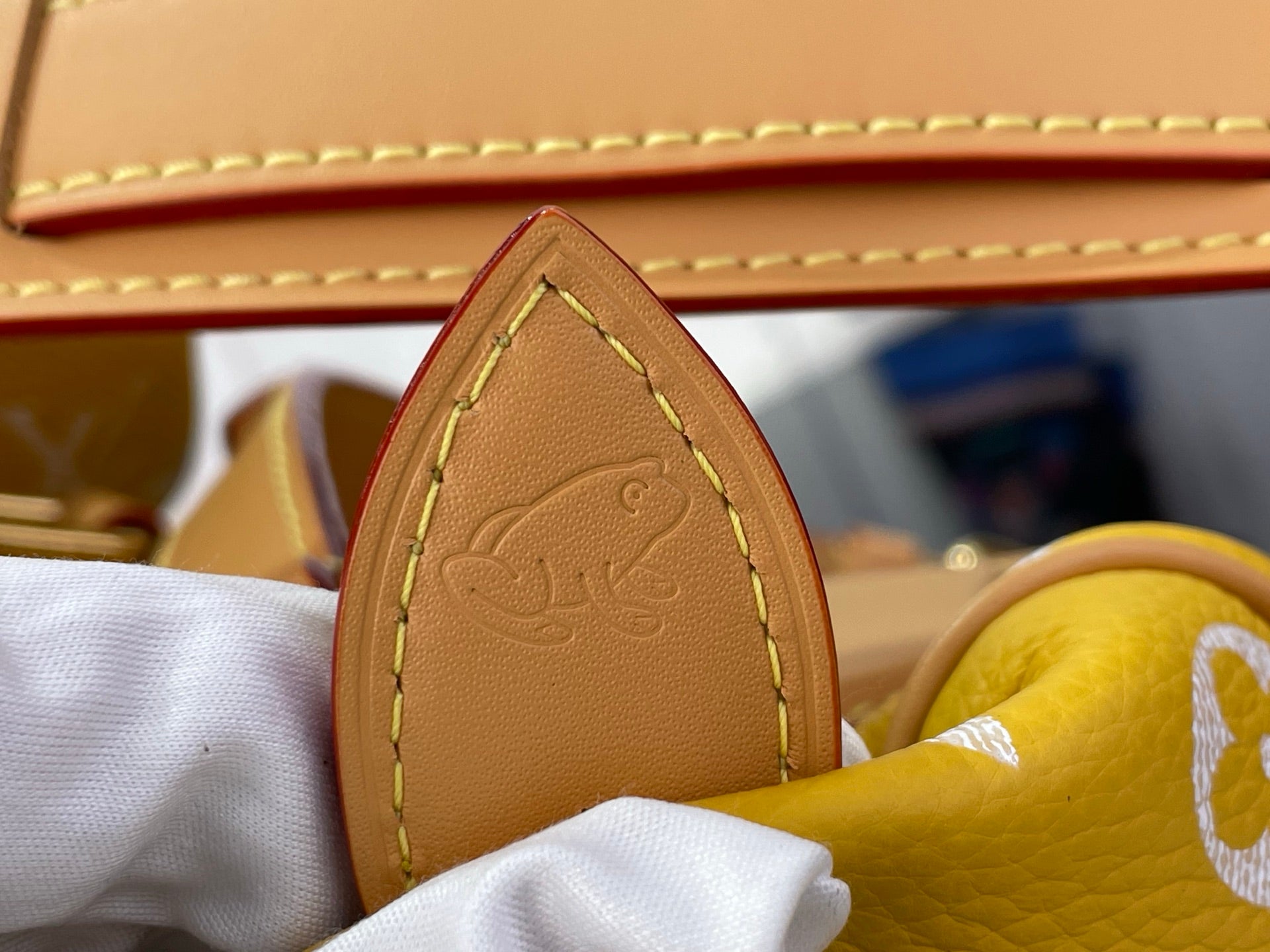 Louis Vuitton bag handle base in tan leather with stitched detail.