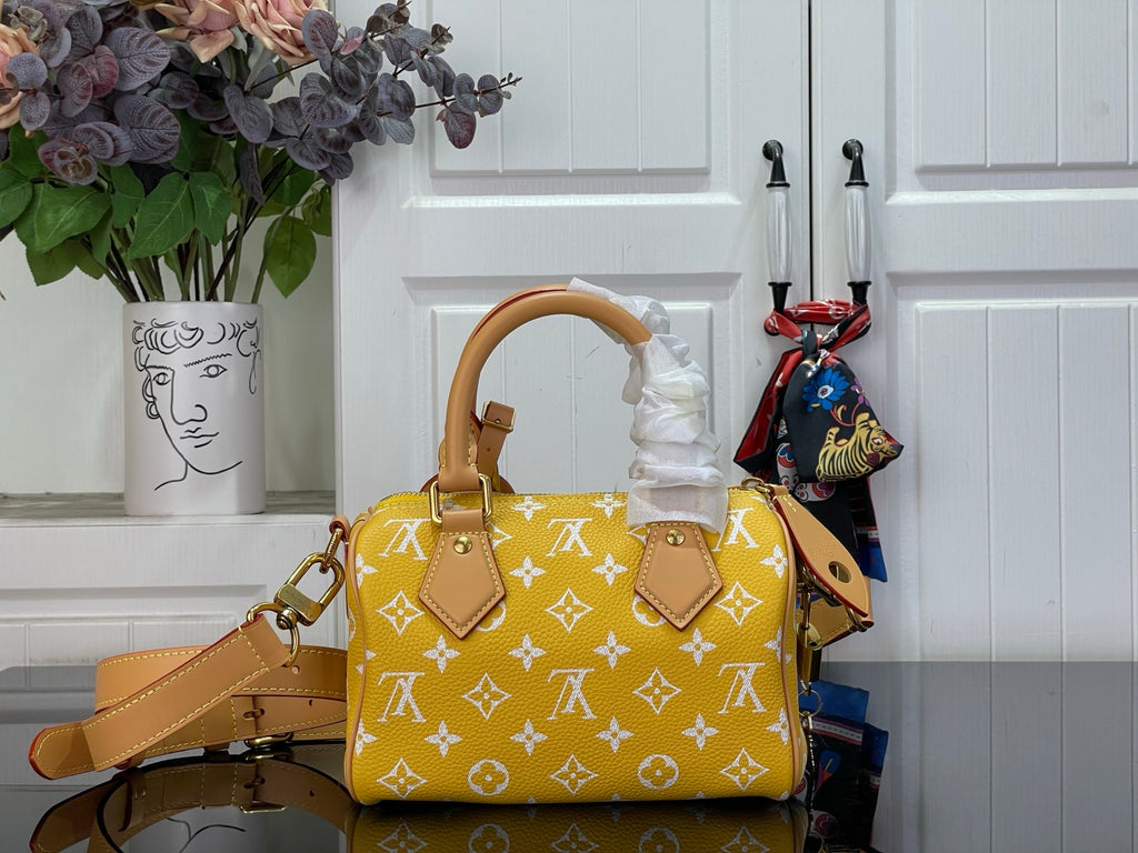Designer handbag with yellow monogram pattern, tan strap, and front flap with tabs