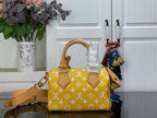 Designer handbag with yellow monogram pattern, tan strap, and front flap with tabs